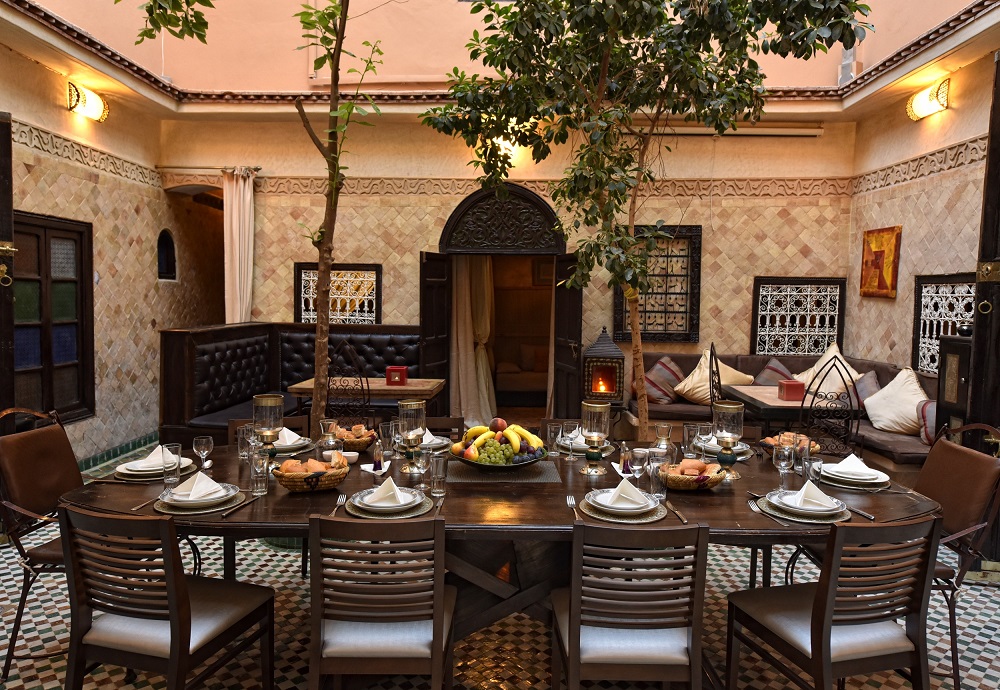 Patio des Riad La Maison Nomade ab 2016 mit großem Tisch in der Mitte und Bänken in den Ecken